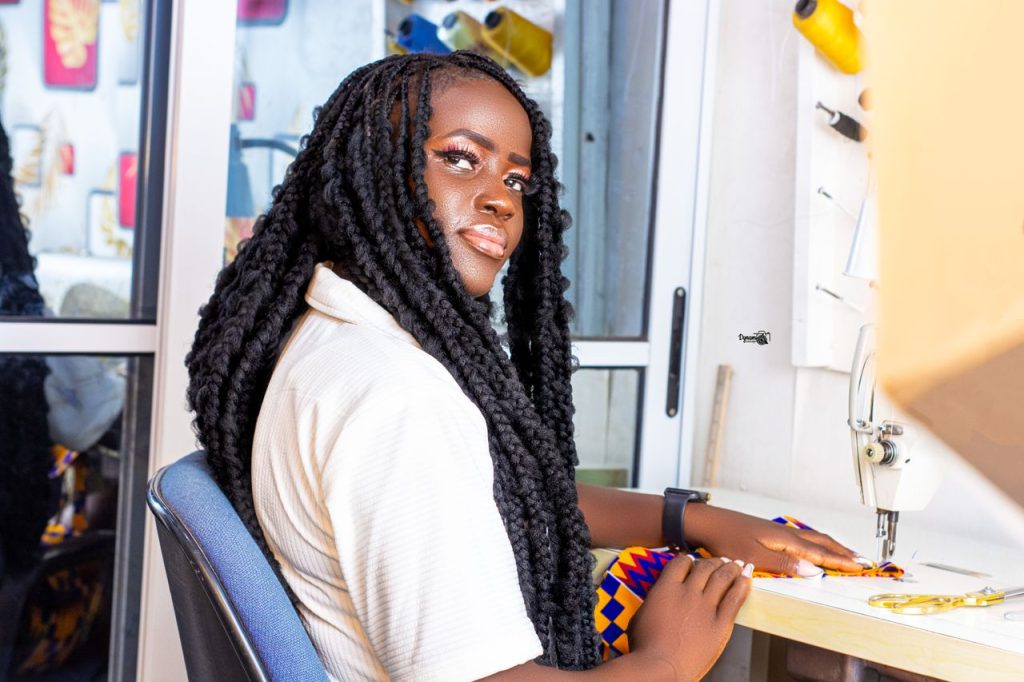 A woman sewing with vibrant fabric in a modern studio, showcasing focus and creativity.