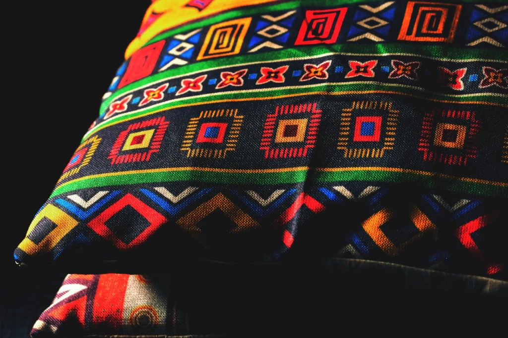 Vibrant pillow featuring bold geometric designs with a tribal aesthetic, rich in colors and patterns.