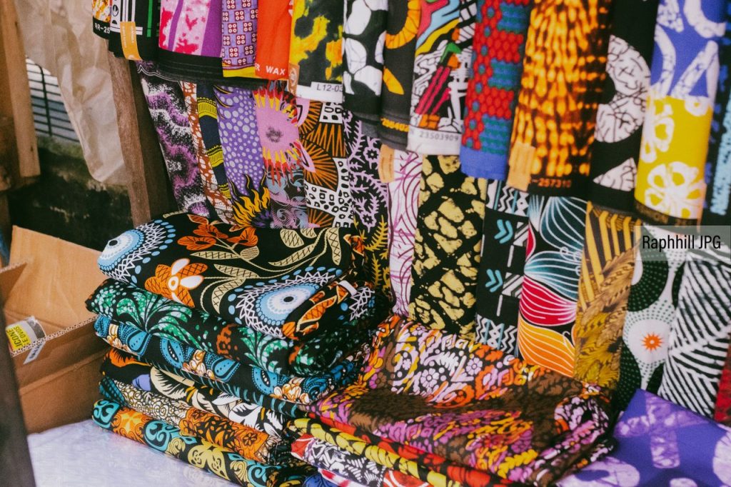 Vibrant African fabrics with various patterns displayed in a market stall.