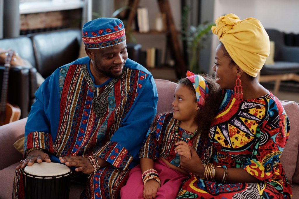A joyful family enjoying bonding time at home in vibrant, traditional African clothing.