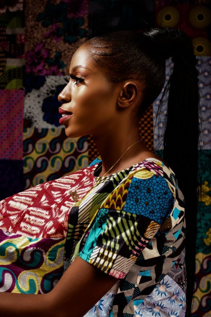 Side view portrait of a woman wearing vibrant traditional African fabric with colorful patterns.